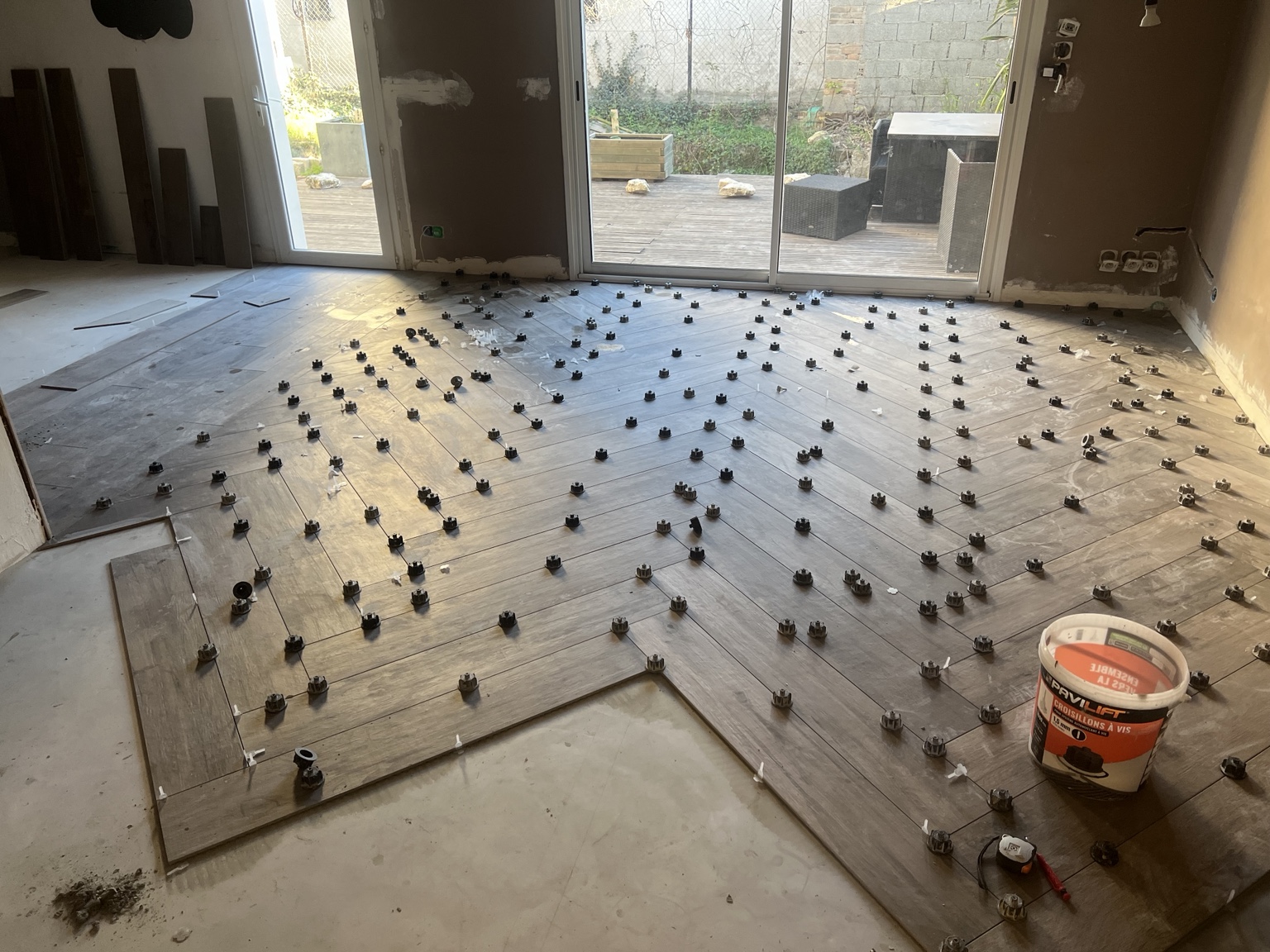 Pose en cours du carrelage 20 × 120 en bâtons rompus avec croisillons de nivellement