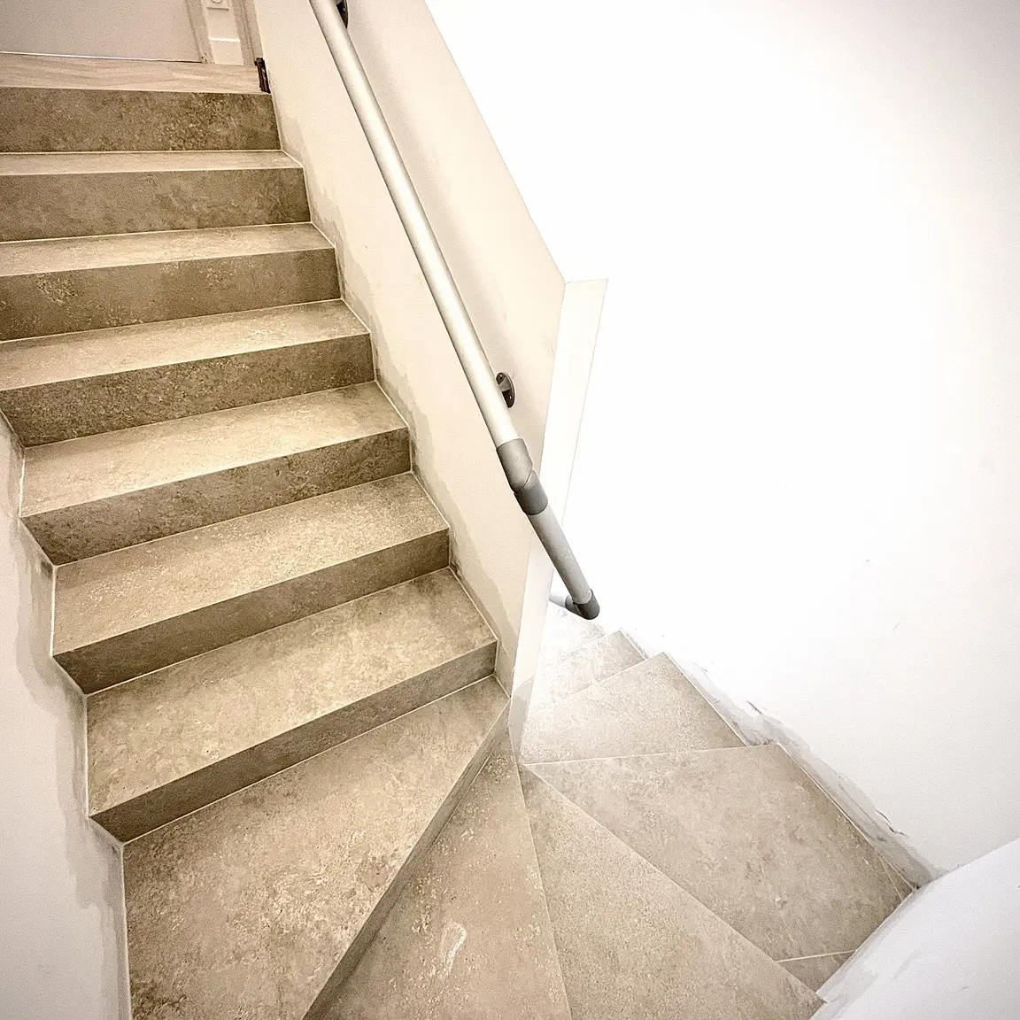 Vue d’ensemble de l’escalier rénové en carrelage imitation travertin à Mouriès