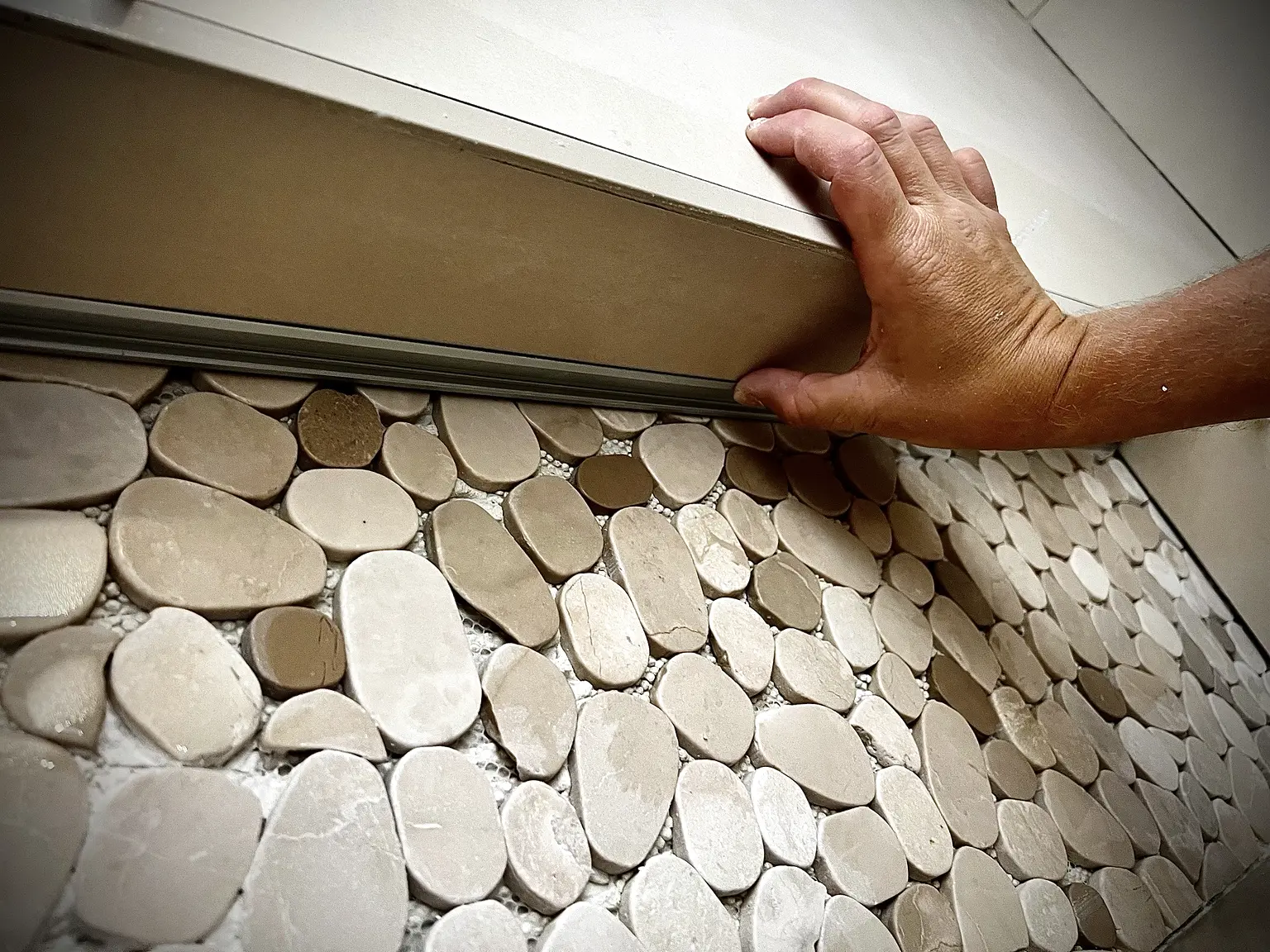 Détail des galets et du profilé dans une niche de douche