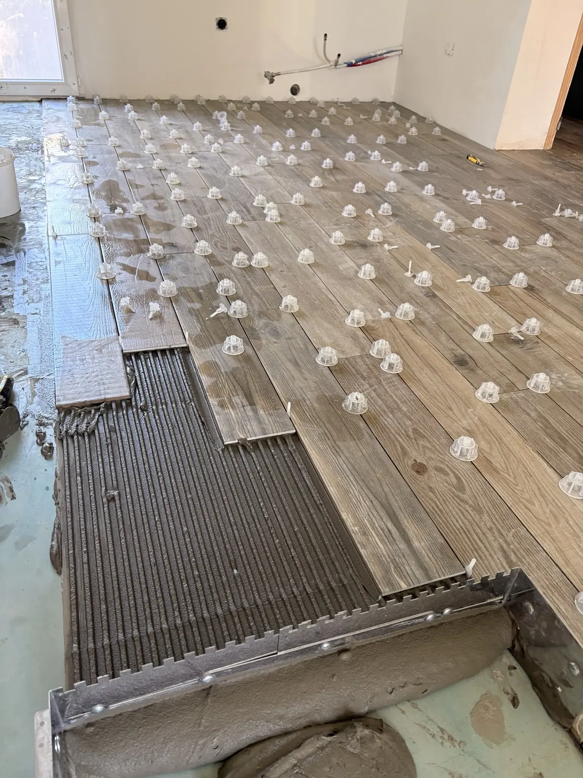 Pose en cours d’un carrelage imitation parquet 15 par 90 avec système de nivellement
